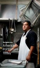man in an apron standing in a kitchen